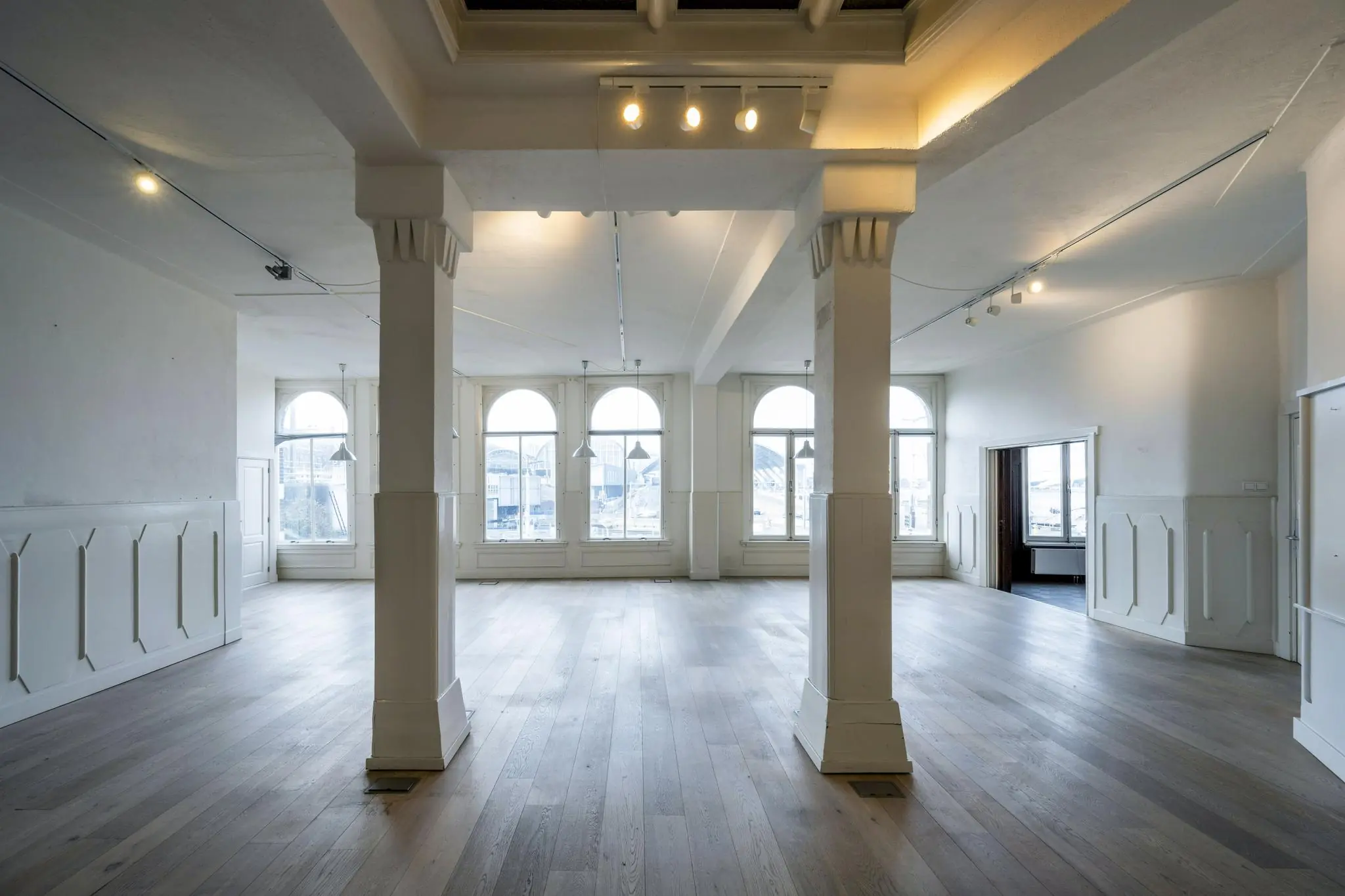 Licht en ruim interieur met hoge plafonds, houten vloer en grote ramen aan de De Ruijterkade.